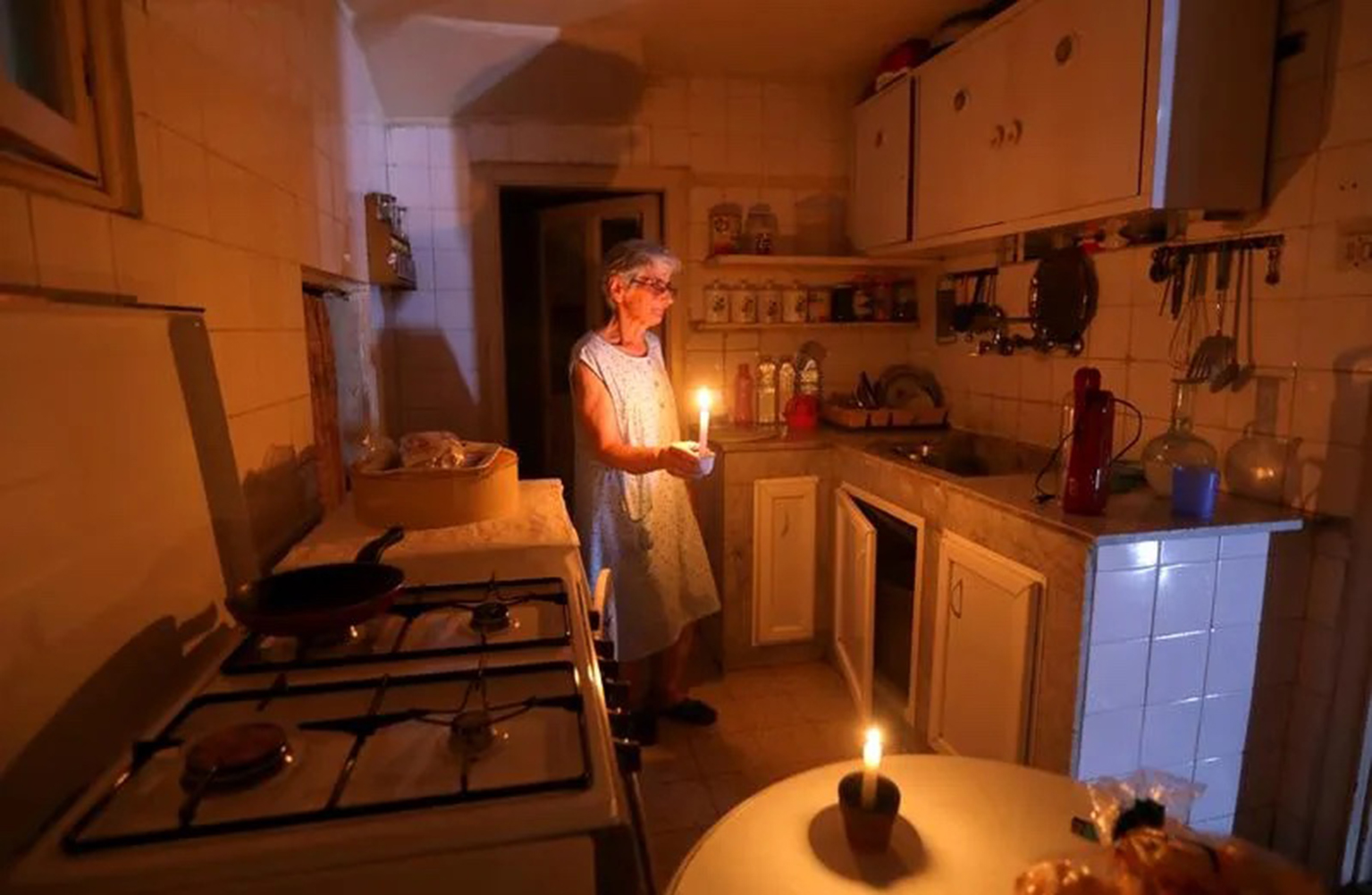 CREDIT REUTERS - MOHAMED AZAKIR__Samira Hanna uses candles to light her kitchen during a power cut in Beirut