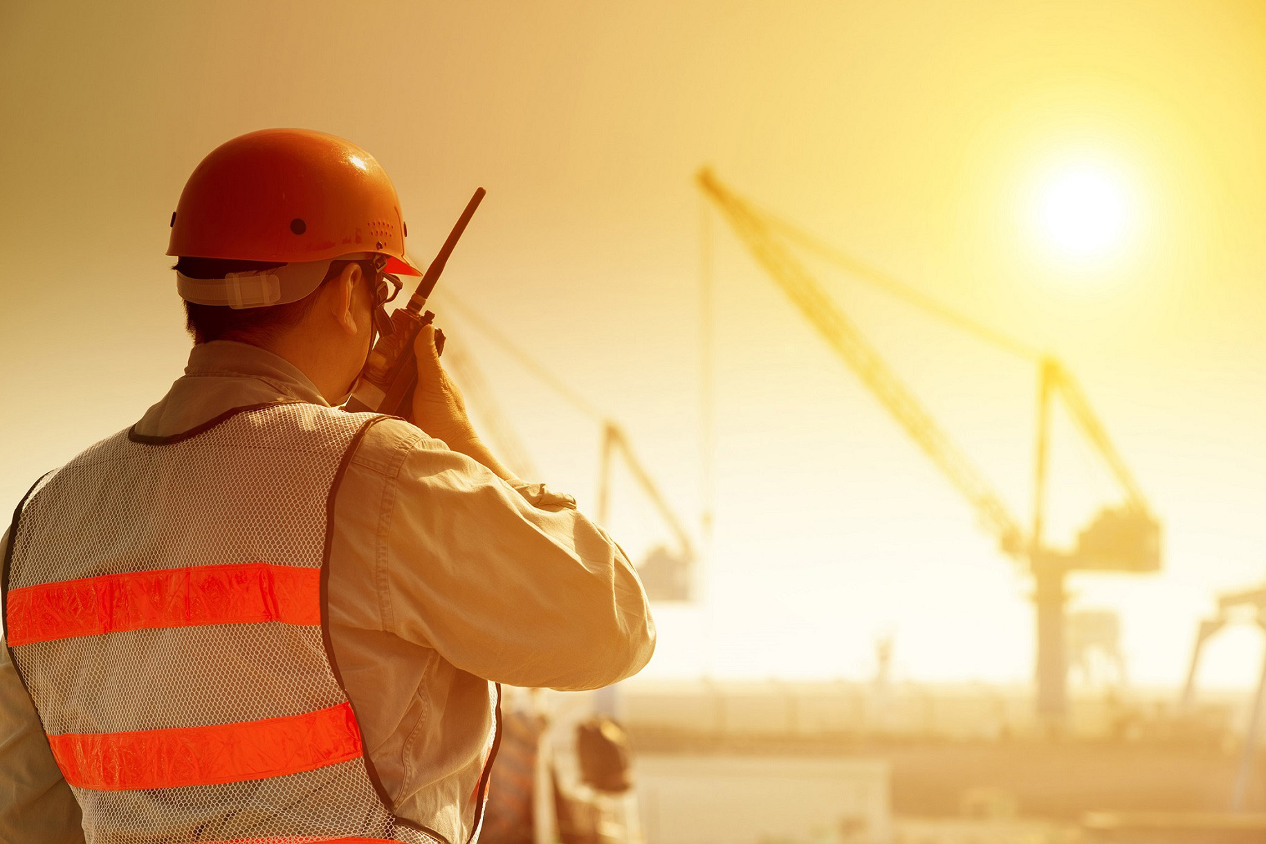 Worker,With,Large,Crane,Site,And,Sunset,Background