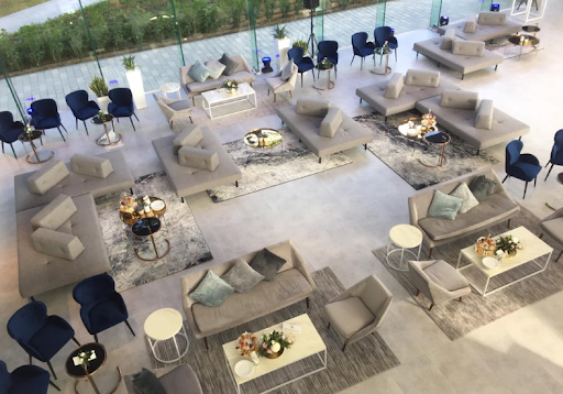 Stylish lounge layout by Desert River Event Rentals with modular grey sofas, navy velvet chairs, and chic coffee tables for a modern event setup
